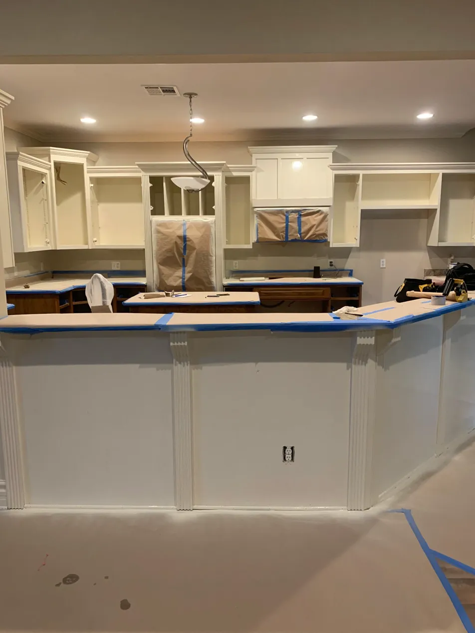 Kitchen cabinet painting in progress with full counter and floor protection
