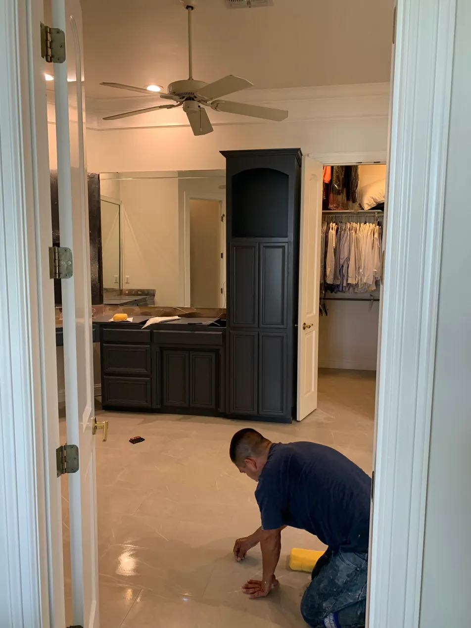 Painter wiping floors after a completed bathroom cabinet refinish